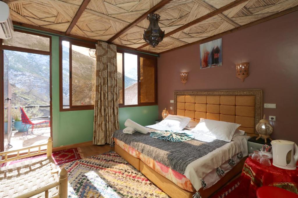 a bedroom with a large bed in a room with windows at Toubkal Garden in Imlil
