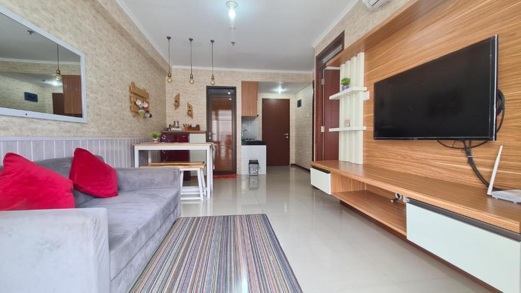 a living room with a couch and a flat screen tv at Gateway Pasteur 2BR tower depan Ruby 7 C in Bandung
