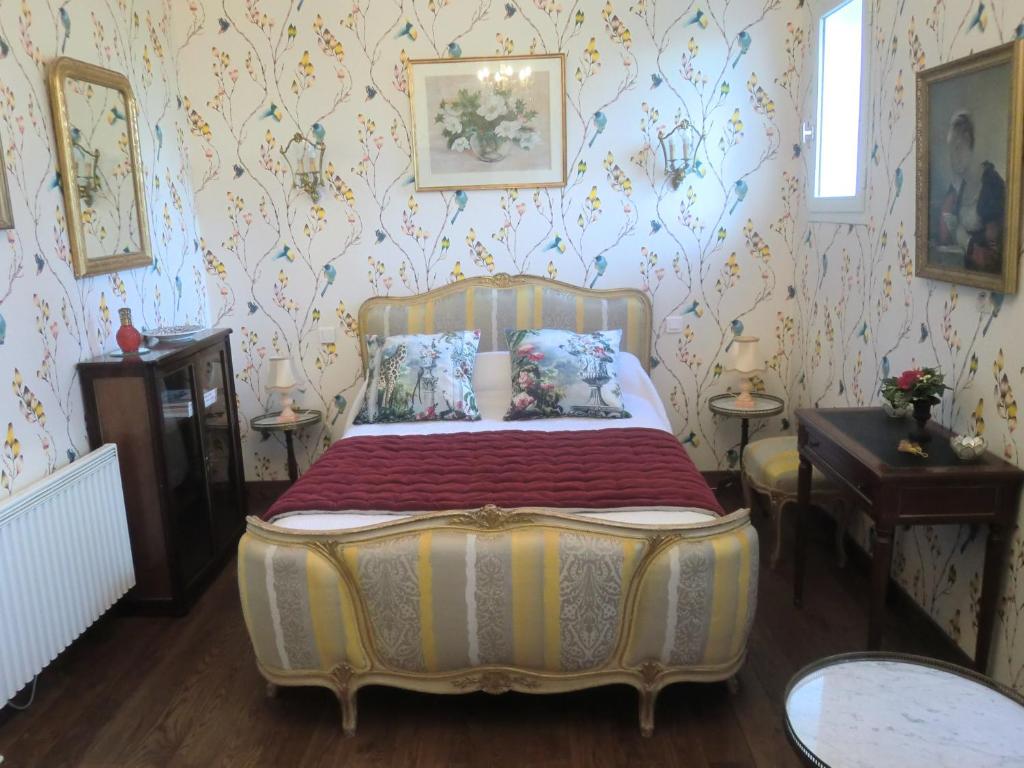 - une chambre avec un lit dans une pièce avec du papier peint dans l'établissement Chambre d'hôtes LA BELLE SAISON, à Villedômer