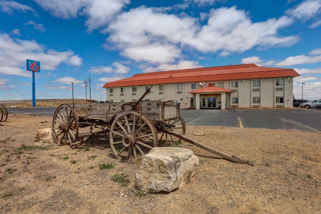 una vieja carreta de madera delante de un edificio en Motel 6-Moriarty, NM, en Moriarty