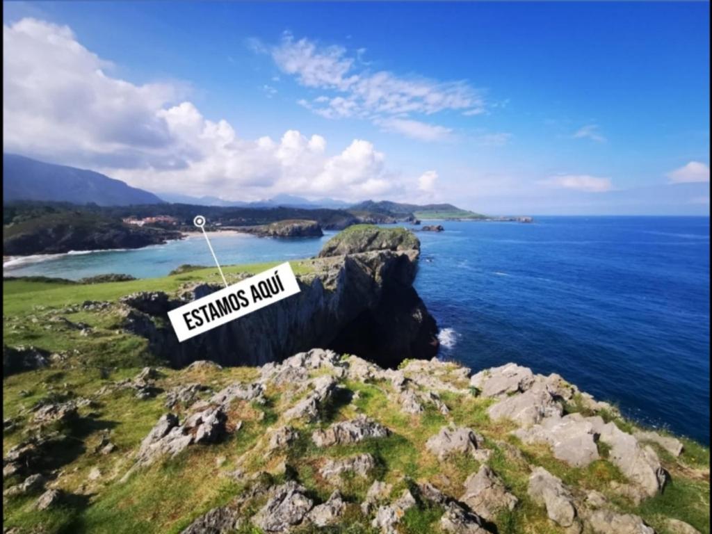 una señal sentada en la cima de una roca cerca del océano en Hostal de la Playa en Barro de Llanes