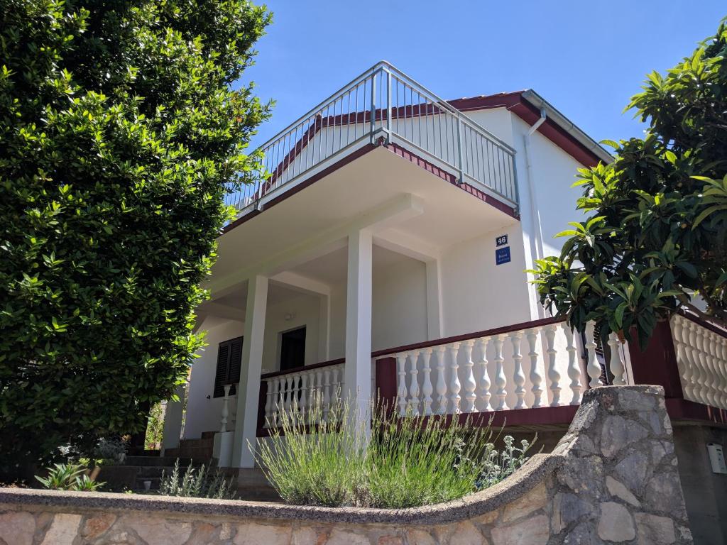 een wit huis met een balkon en bomen bij Apartment Lordanic Zaglav, Dugi otok in Zaglav