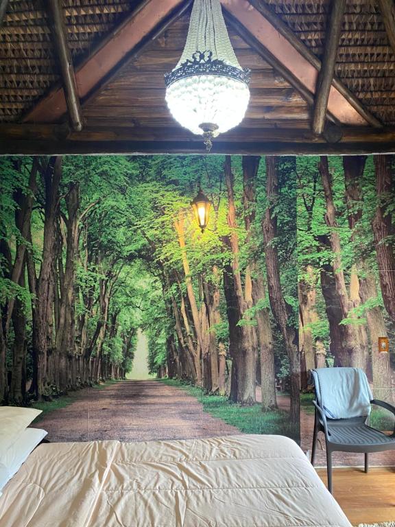 een slaapkamer met een schilderij van een bosweg bij Cabana Do Zuza in Campos do Jordão