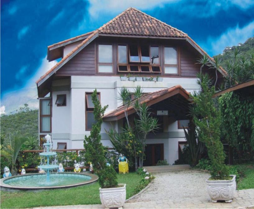 ein Haus mit einem Brunnen davor in der Unterkunft Hotel Dominguez Master in Nova Friburgo