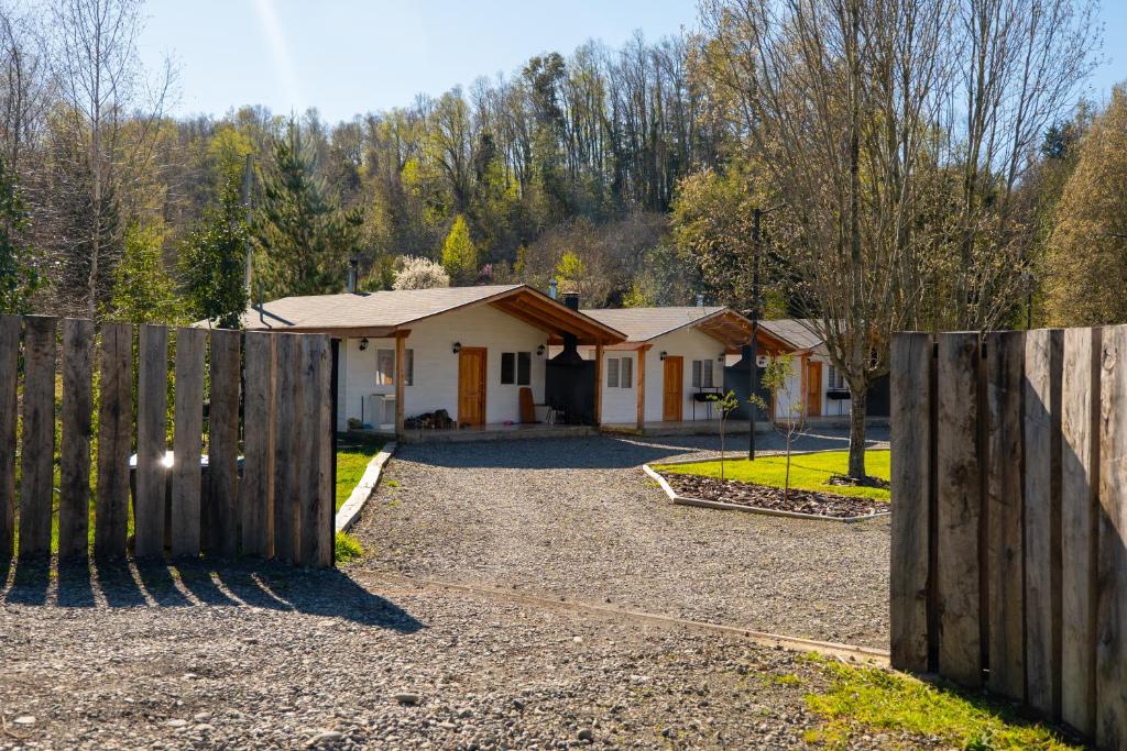 a house with a wooden fence in front of a driveway at Cabañas Canto de Calafquen in Licán Ray