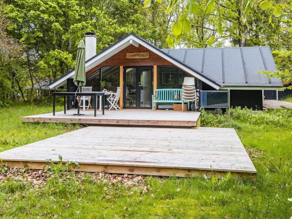 ein Haus mit einer Holzterrasse, einem Tisch und einer Terrasse in der Unterkunft 6 person holiday home in Glesborg in Glesborg