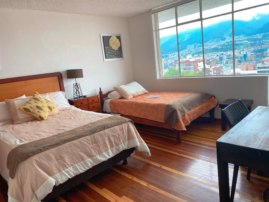 1 dormitorio con 2 camas y ventana en Bed and Breakfast La Uvilla, en Quito