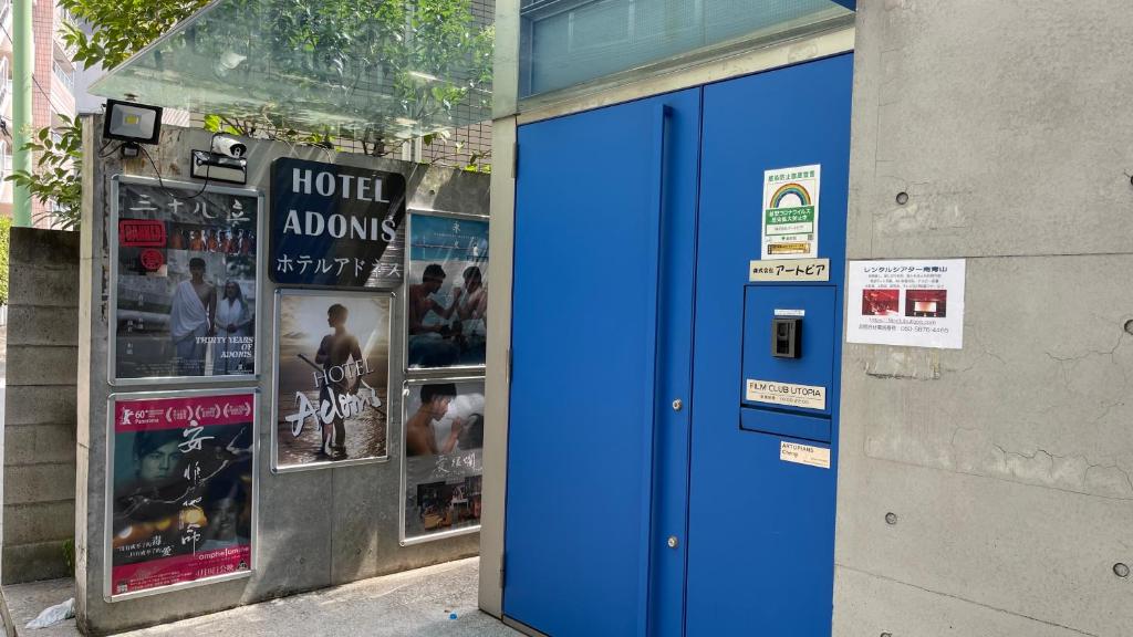 a blue door on the side of a building with posters at Hotel Adonis Tokyo - Dormitory Share Room For Male Only At City Center in Tokyo