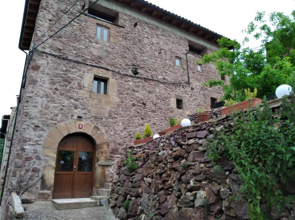 een oud stenen gebouw met een deur en een stenen muur bij Casa Fabiana in Montenegro de Cameros