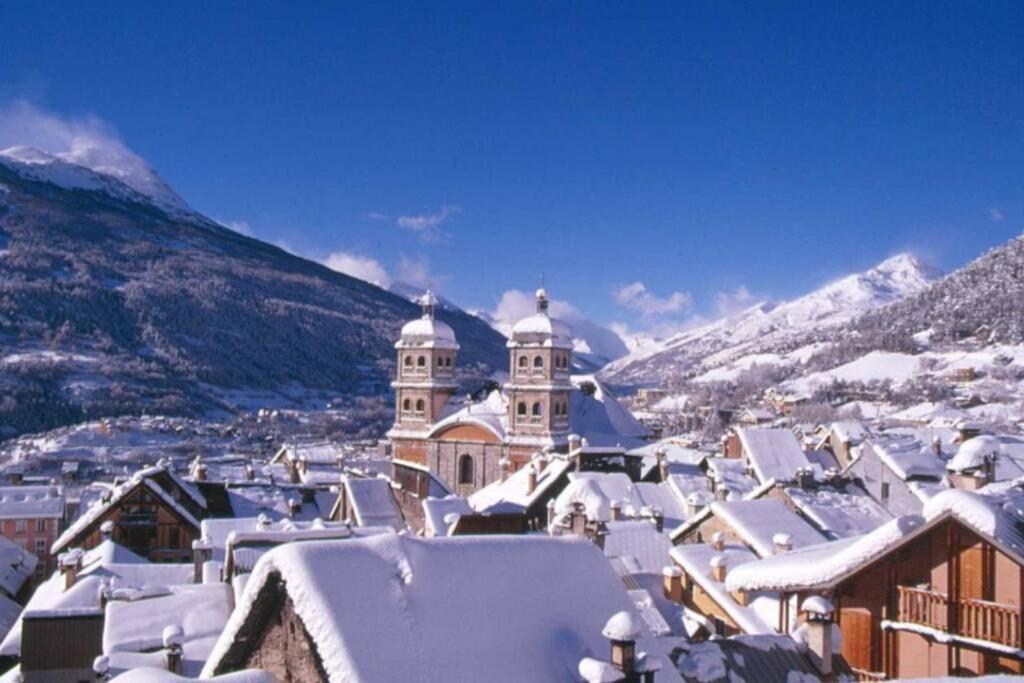 a town covered in snow with mountains in the background at Studio idéal 2 personnes et/ou avec 2 enfants in Briançon