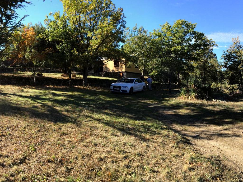 een witte auto geparkeerd in een tuin met bomen bij RIBES - Chalet Gîte au coeur de la nature in Sournia