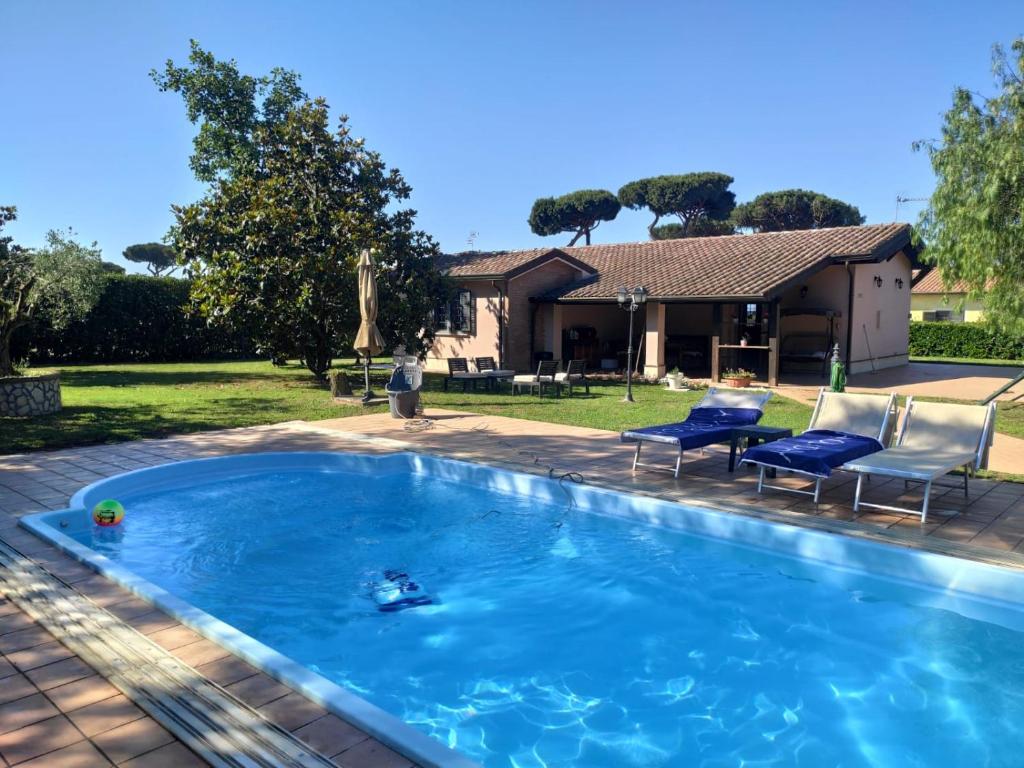 a swimming pool with two chairs and a house at Villa Bella in Sabaudia