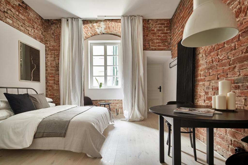 a bedroom with a brick wall and a bed and a table at OLD NEW - Main Square in Krakow