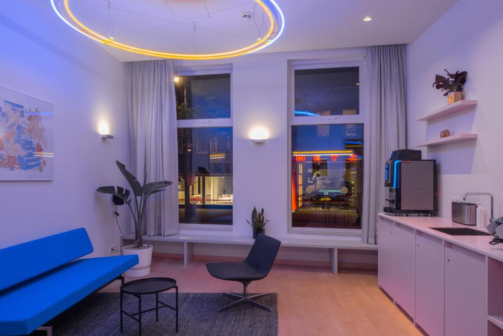 a living room with a blue couch and a kitchen at 171. Urban Design Hotel in Rotterdam