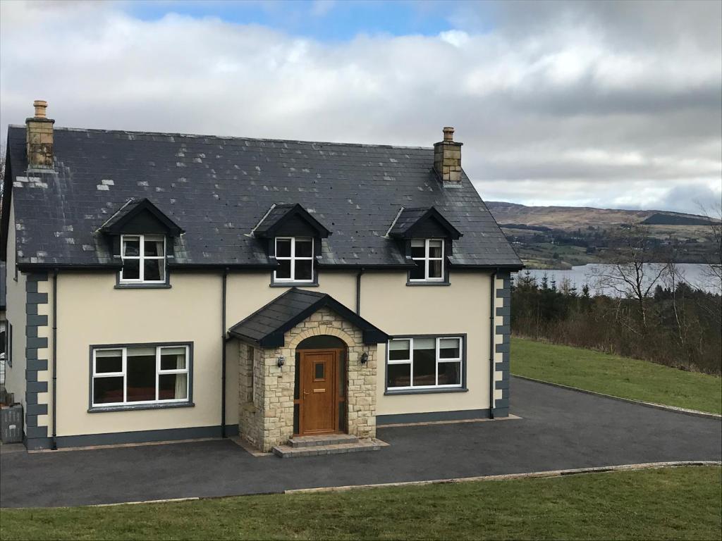 een wit huis met een bruine deur op een oprit bij Loughview House in Donegal