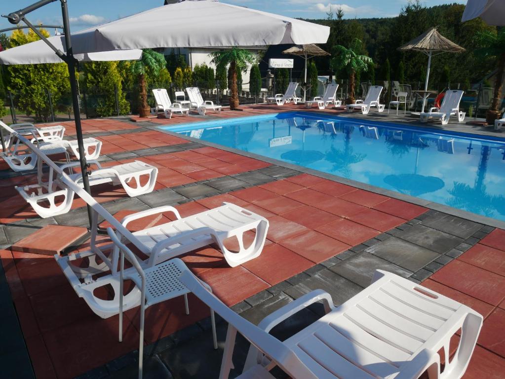 a swimming pool with lounge chairs and umbrellas at Dom Weselny Bartpol Family&SPA in Gródek Nad Dunajcem