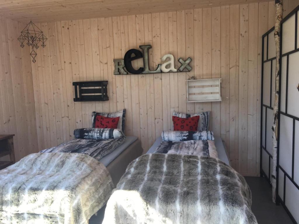イナリにあるNature Experience Glampingのベッド2台 木製の壁の部屋