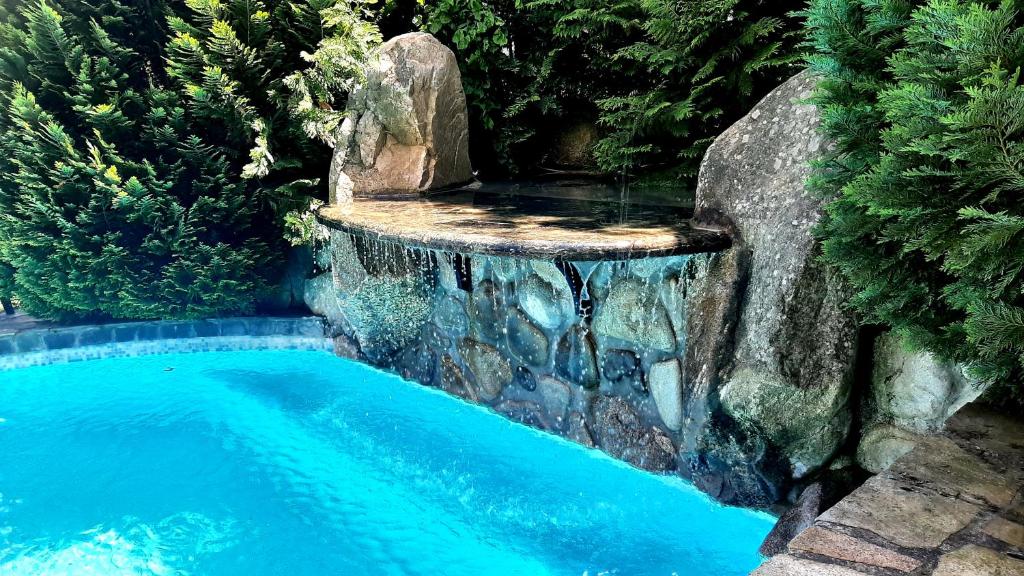 a swimming pool with a waterfall next to a stone wall at Villa Anna Luxury Lake Residence in Shtarkelovo Gnezdo