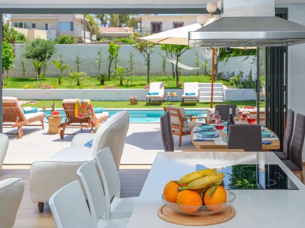 a table with bananas and oranges on it on a patio at Villa Belle Helene Kalamaki Chania in Kalamaki Chanion