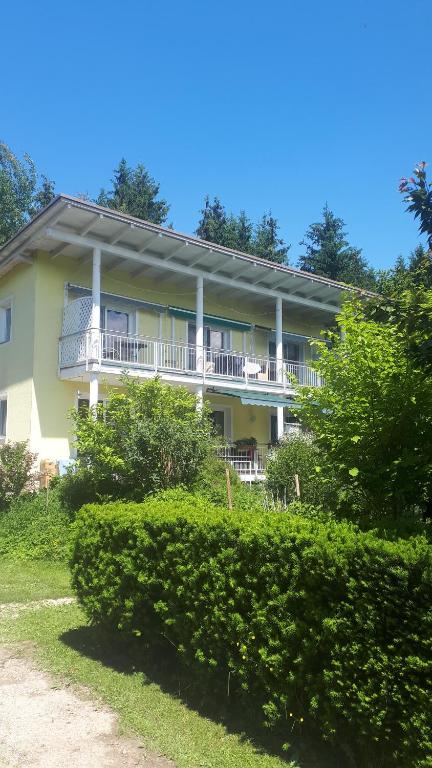 Großes gelbes Haus mit Balkon und Büschen in der Unterkunft Apartment Orlitsch in Klagenfurt am Wörthersee