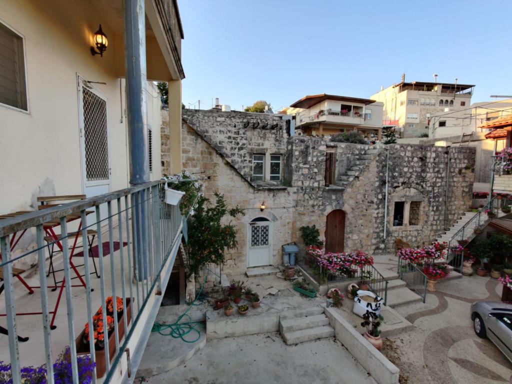 un antiguo edificio de piedra con un balcón con flores en Mi'ilya CHOCOLATE HOUSE Guest house, en Mi‘ilyā