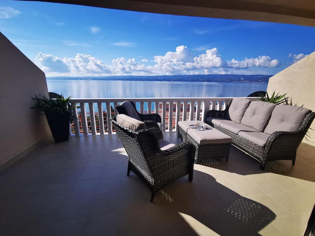 a balcony with a couch and chairs and a view of the water at Apartman Dalmatia in Duće