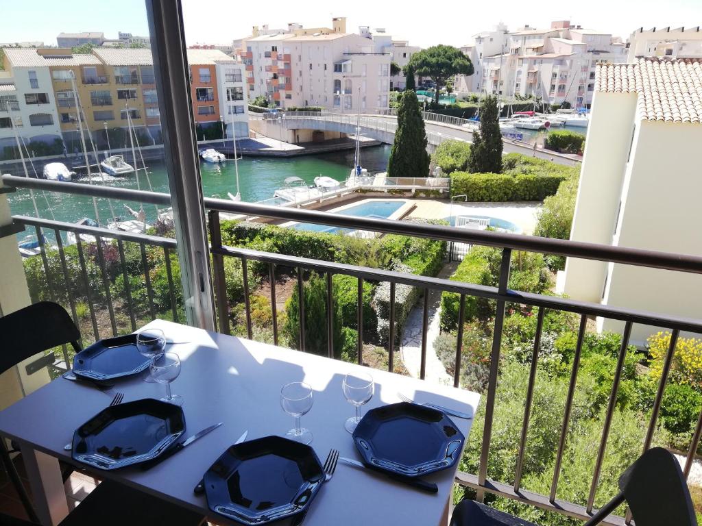 uma mesa com pratos e copos numa varanda em Appartement Studio cap d'agde avec vue port et piscine em Cap d'Agde