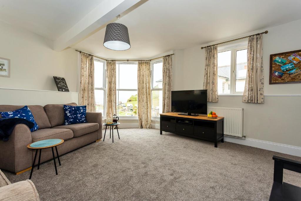 a living room with a couch and a flat screen tv at Seagulls Loft, Grove Apartments in Ilfracombe