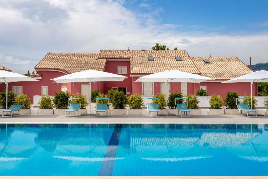 una piscina del resort con sedie e ombrelloni di Dipladenia Garden Country Resort a Mascali