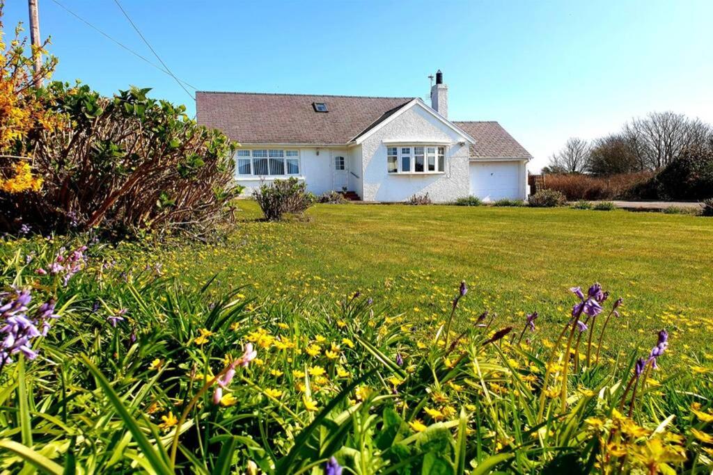 een wit huis met een tuin met bloemen bij TIRNANT- 3 Bed - GROUND FLOOR ROOMS -DOG FRIENDLY in Trearddur