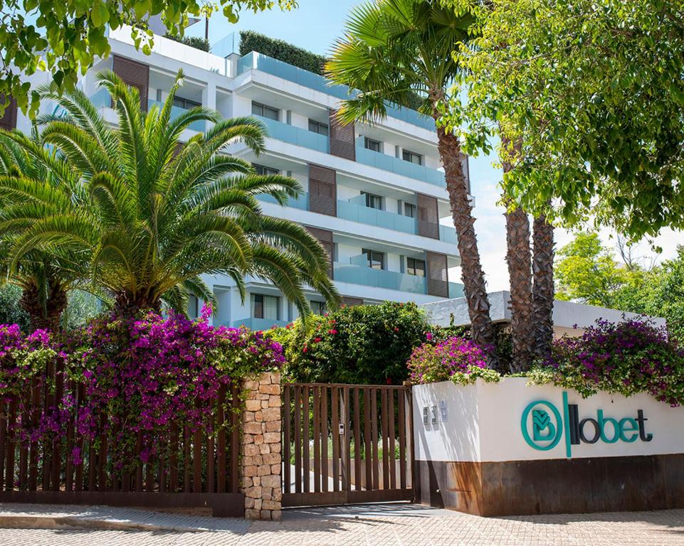un hotel con una valla y flores frente a un edificio en Apartaments B-Llobet Sun & Confort, en Ibiza