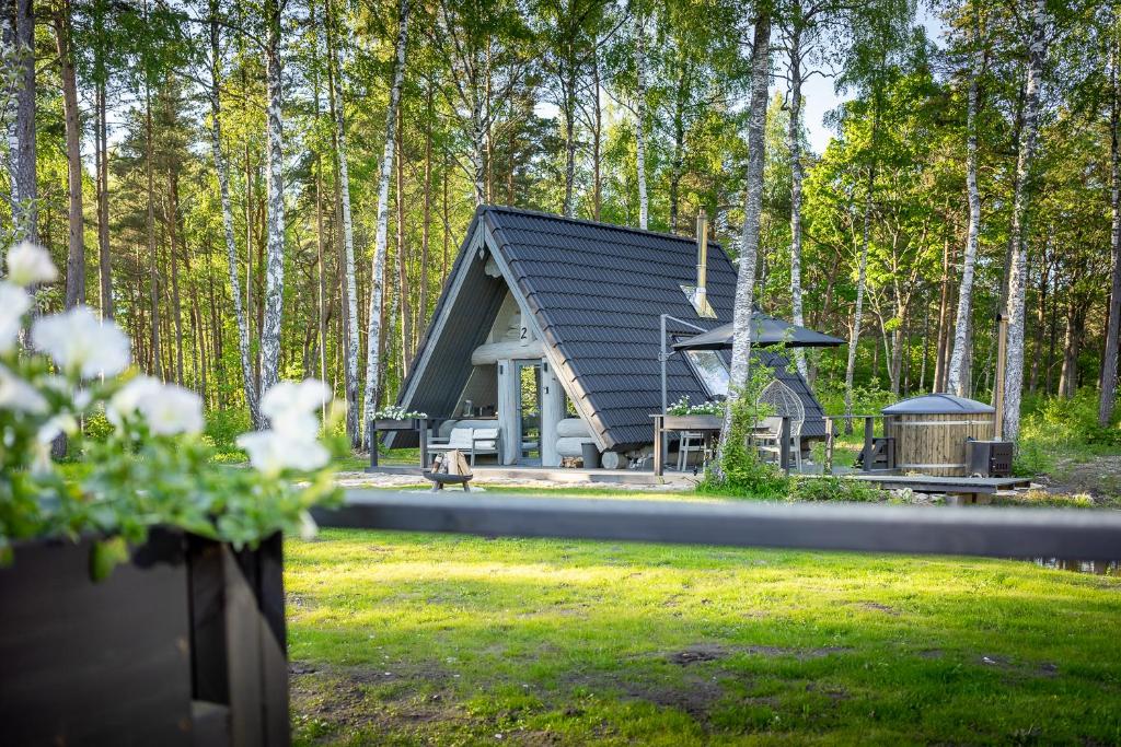 a cabin with a black roof in the woods at Nordicstay Noarootsi Saunahouse in Paslepa