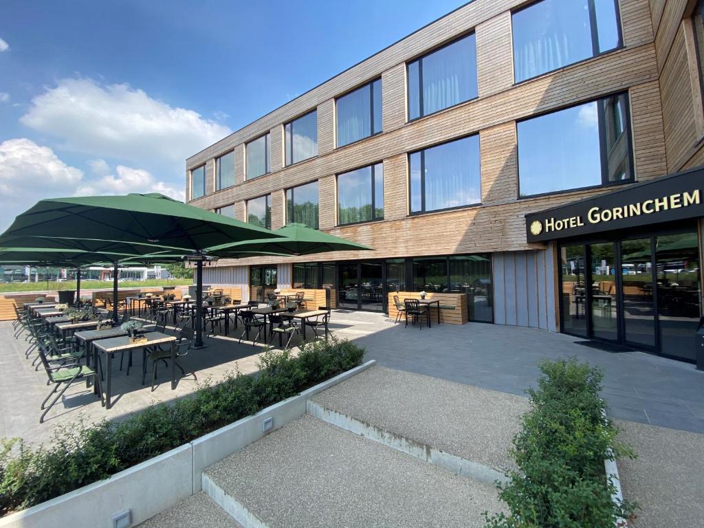 a building with tables and green umbrellas in front of it at Hotel Gorinchem in Gorinchem