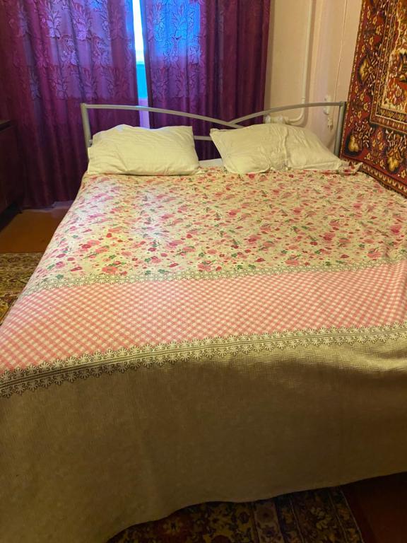 1 cama con edredón de flores y almohadas en В Самом центре en Myrhorod