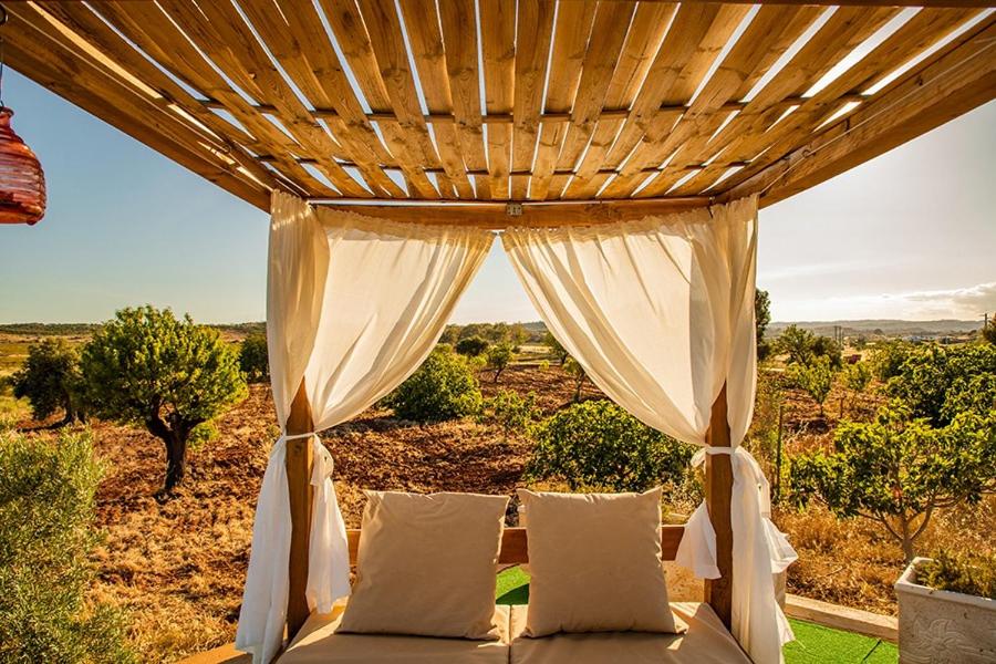a bed under a wooden pergola with a view at Casa Natura in Castro Marim