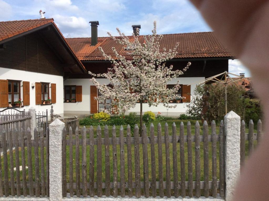 ein Holzzaun vor einem Haus mit einem Baum in der Unterkunft Ferienwohnung Hörmann in Langdorf