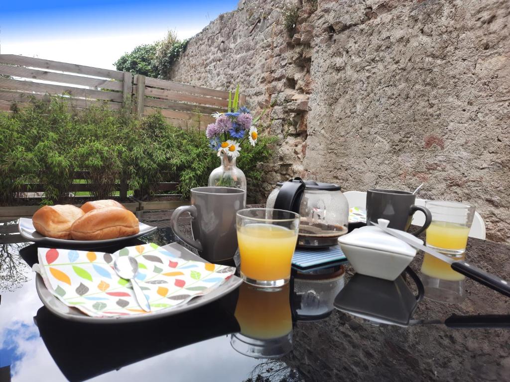 uma mesa com pequeno-almoço de sumo de laranja e pão em kérentrée - Appartement en centre ville avec terrasse et parking privé em Pont-lʼAbbé