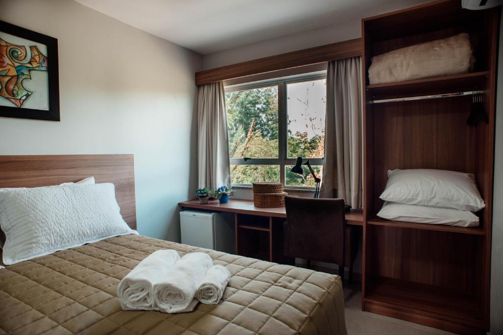 1 dormitorio con cama, escritorio y ventana en Wallér Hotel & Eventos Inn Lajeado, en Lajeado
