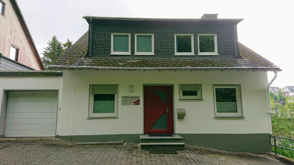 una pequeña casa blanca con una puerta roja en Ferienhaus Winterberg en Winterberg