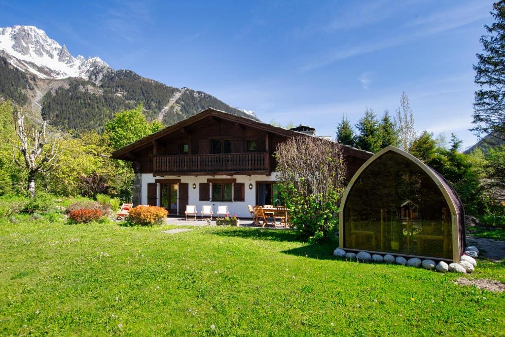 Chalet 280m2 Sauna Cinema 12pax Heart of Les Praz في شامونيه مون بلان: منزل بباب زجاجي في ساحة