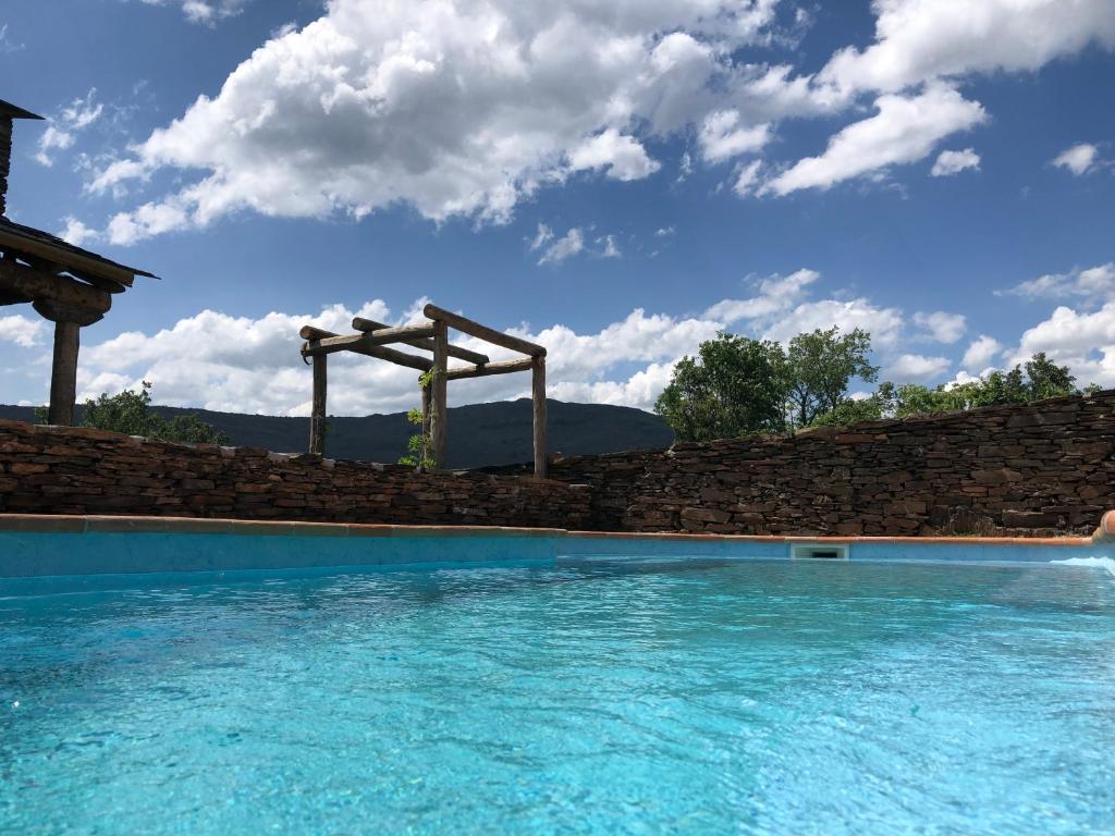 una piscina con una pared de piedra y agua azul en Refugios Del Valle Negro, en Campillo de Ranas
