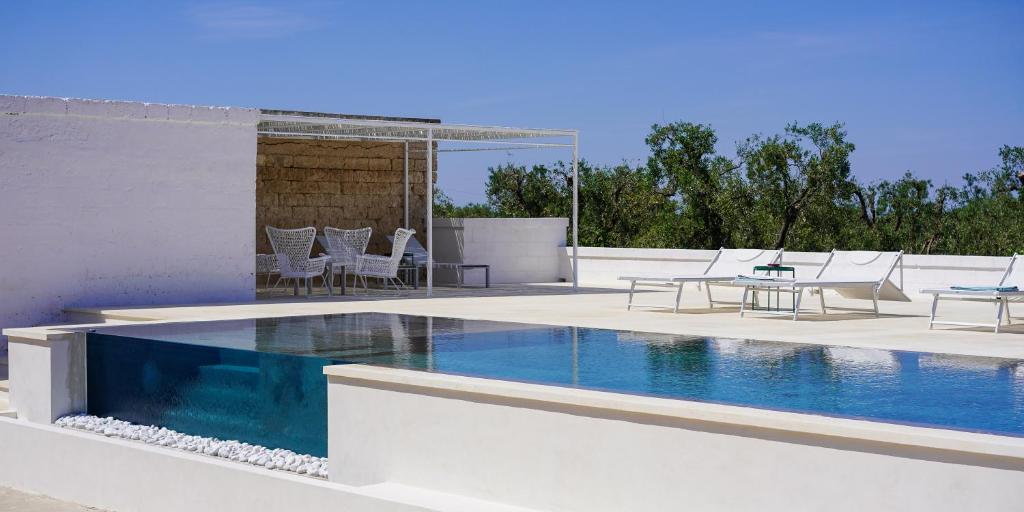 una piscina con sedie e un tavolo accanto ad essa di Masseria Pezze Galere Piscina privata a Montalbano