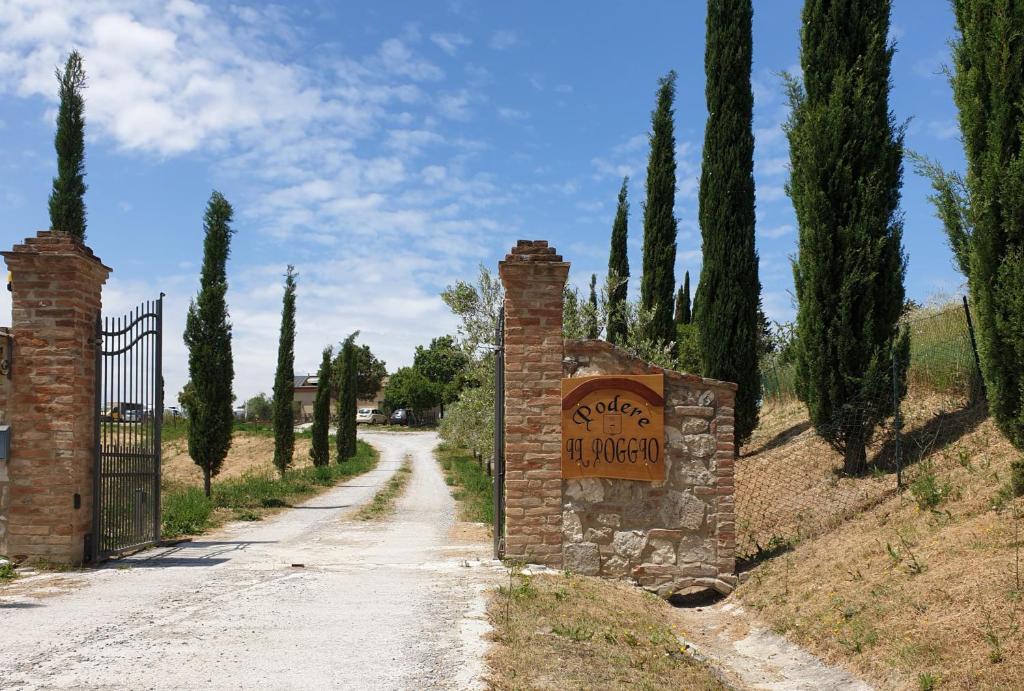 een poort naar een oprit met een bord op een weg bij Podere il Poggio in Asciano