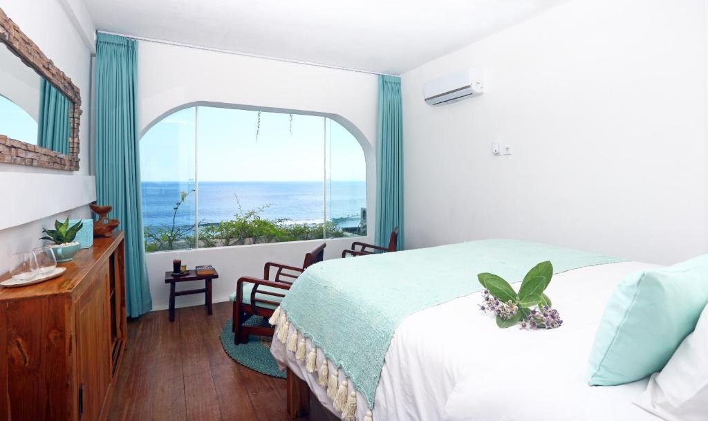 ein Schlafzimmer mit einem Bett und einem großen Fenster in der Unterkunft Bale Bingin Beachfront Stay in Uluwatu