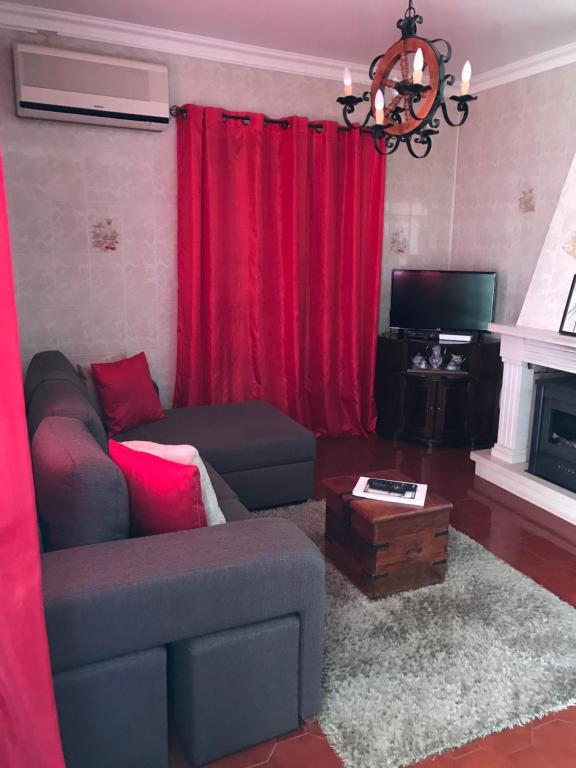 a living room with a couch and red curtains at Casa da tia Bina in Monsaraz