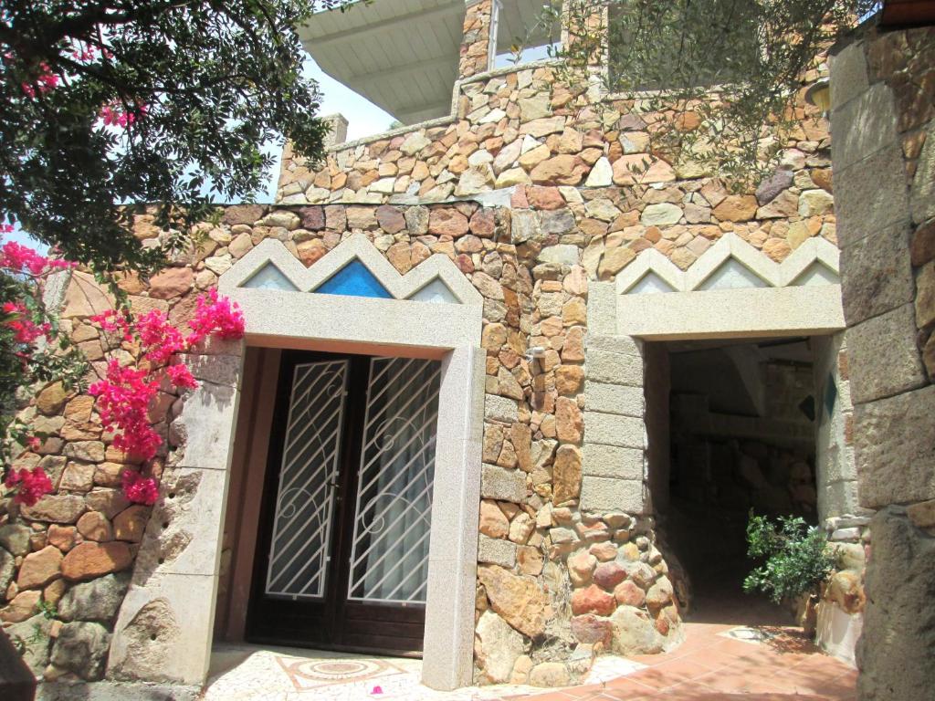 un edificio de piedra con dos puertas de garaje y flores en Sardinia Yellow House, en Solanas