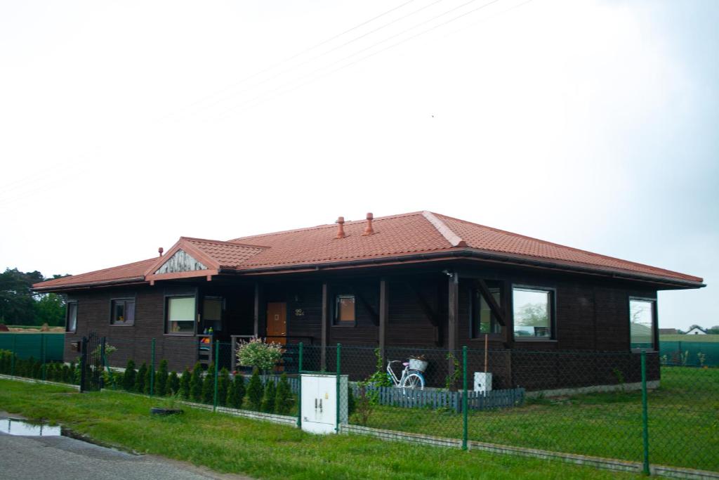 een bruin huis met een rood dak bij Letnisko nad Gopłem in Skulsk