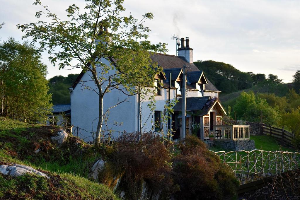 a large white house with a chimney on a hill at Ardmore House B&B in Lochinver