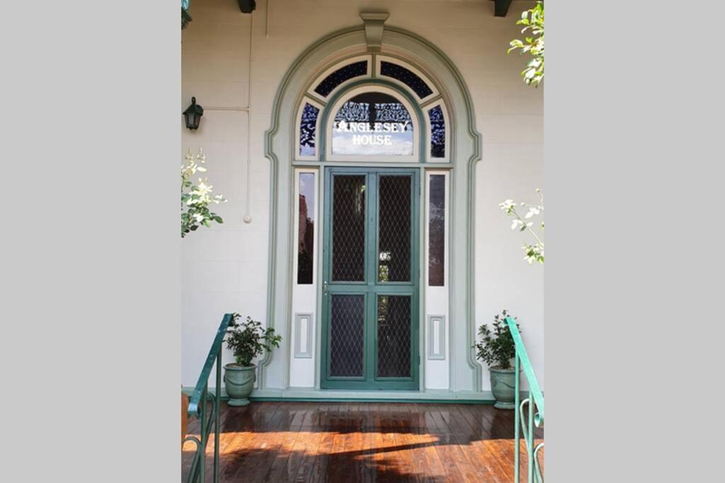 uma entrada para uma casa com uma porta azul em Anglesey House Iconic Forbes CBD Heritage Home em Forbes