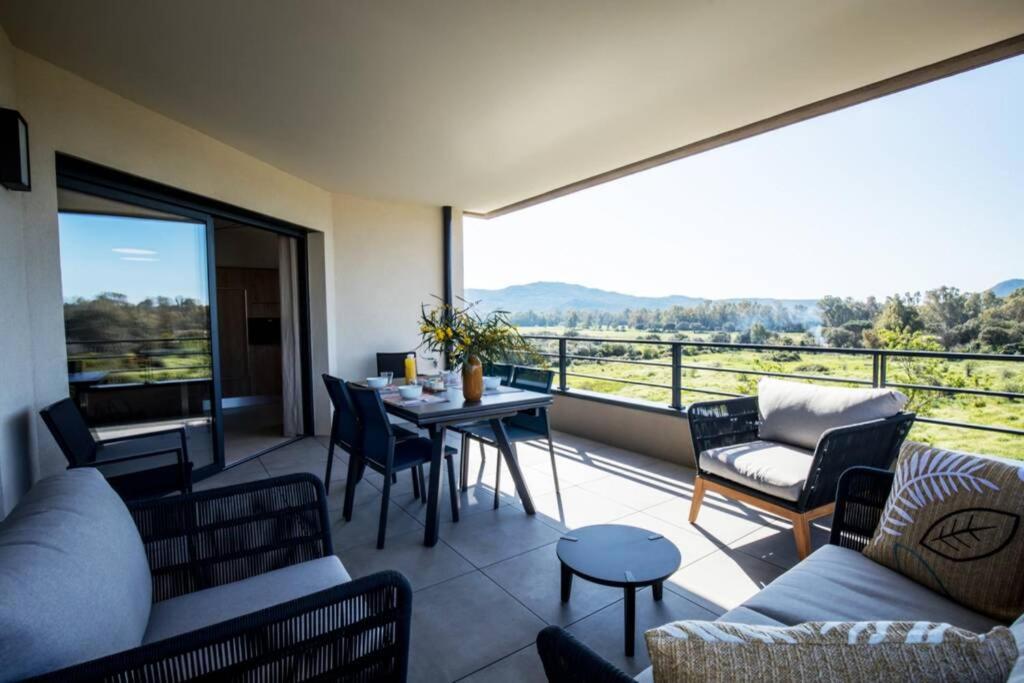 - un salon avec un balcon doté d'une table et de chaises dans l'établissement Les 3 baigneuses : Appartement 2 chambres, neuf proche de toutes commodités, à Porto-Vecchio